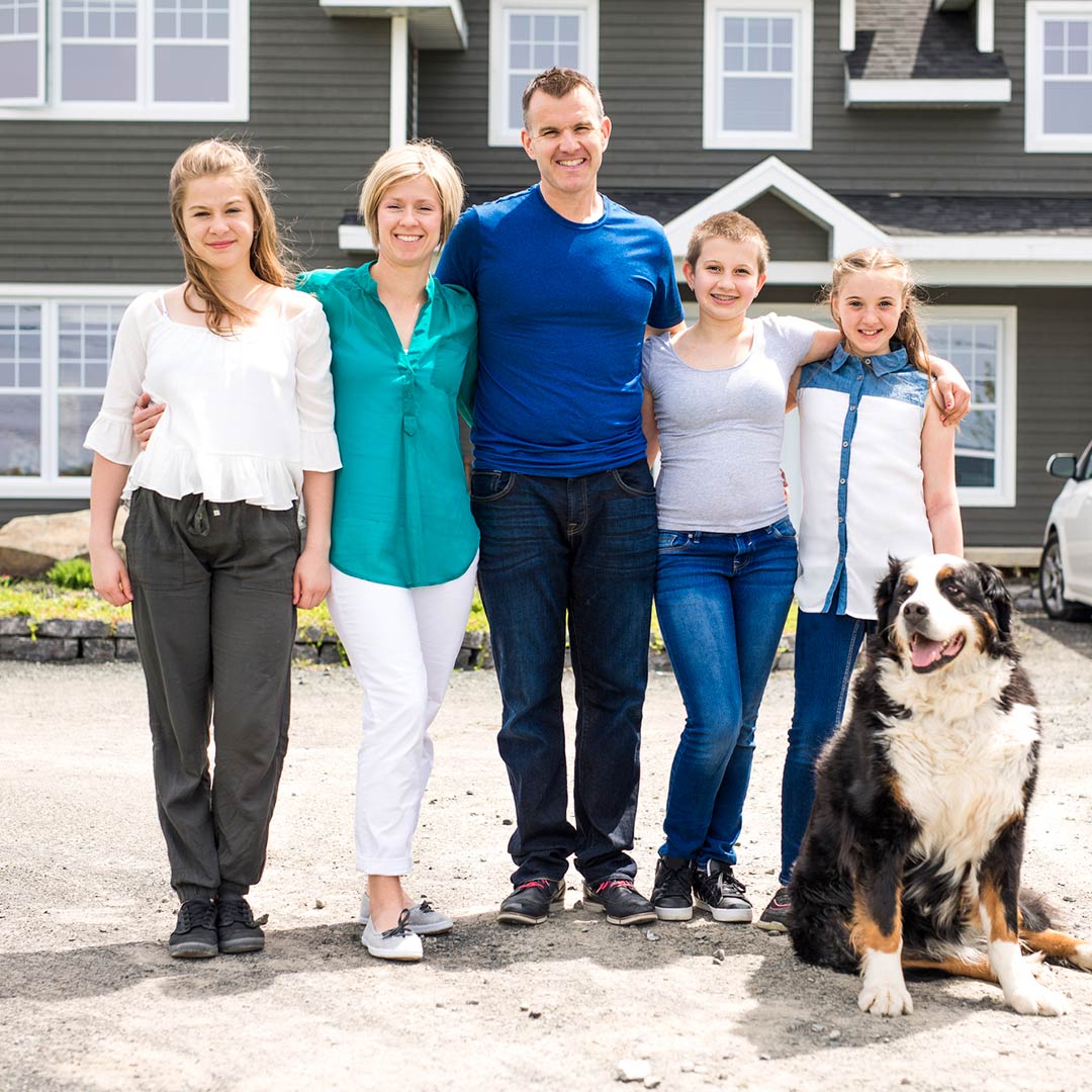 Family standing in front of their home with their dog